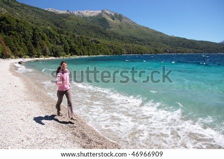 A beautiful woman runs along a blue lake in the Patagonia region of Argentina.