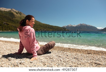 A woman sits at the edge of a clear blue lake in southern Argentina.