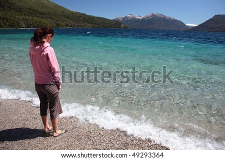 A woman stands at the edge of a clear blue lake in southern Argentina.