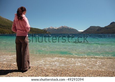 A woman stands at the edge of a clear blue lake in southern Argentina.