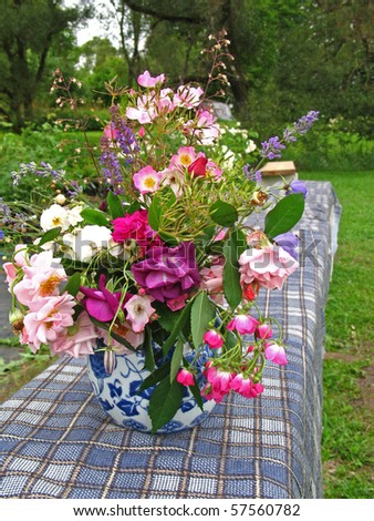 Summer end flowers - wild roses in blue vase on long blue bench