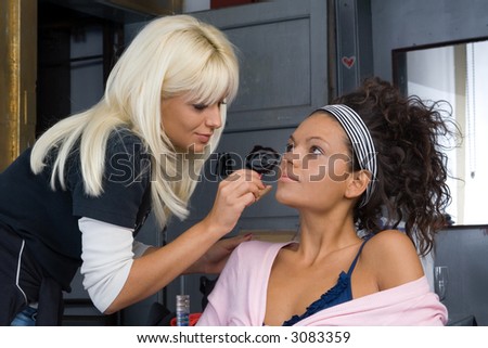 beautiful brunette girl model, while make-up before shooting session (professional make-up artist doing his job)