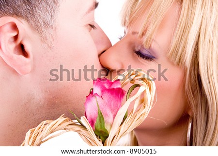 young couple in love kissing, (behind red rose - focus on rose), isolated on white background