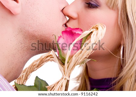 young couple in love kissing, behind red rose, isolated on white background