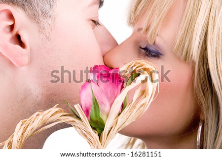 young couple in love kissing behind red rose, isolated on white background