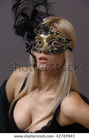 Portrait of beautiful young woman with Venetian mask on her face. Masquerade concept. Studio shot. Dark background.