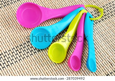 A set of measuring spoons made of colored plastic on a bamboo mat