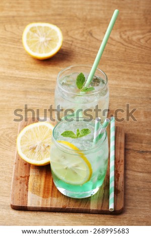 cold soft drink from apple syrup and mint with green spoon on wooden board