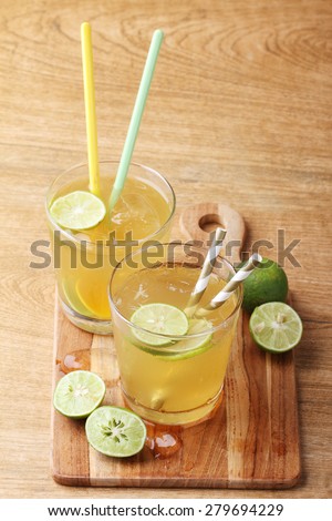 cold gold soft drink from lime and honey with gold straw on wooden board