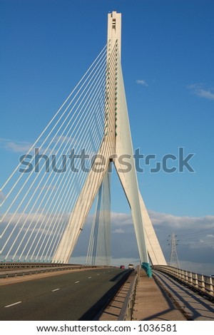 Modern suspension bridge with tall concrete upright support and steel cables.