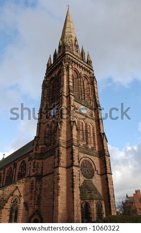 Portrait view of Large Sandstone church tower complete with round window,arched windows and a clock