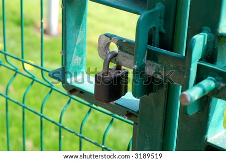 Padlock locking a wire mesh security gate