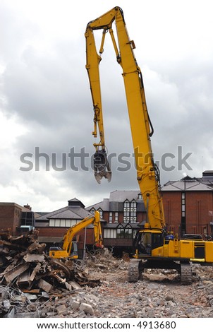 Heavy machinery on a demolition site with lots of rubble and twisted metal.