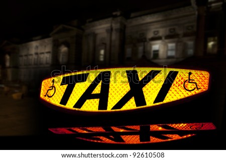 Taxi sign lit up showing the word Taxi and the disabled symbol with a reflection