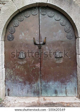 The large copper door includes words of welcome on the large door knockers and twelve shields symbolising the calendar months, in Hum, Croatia