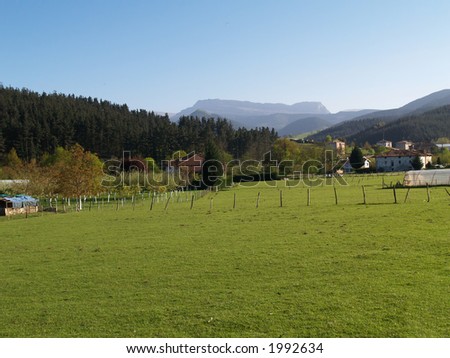 A green valley in the Basque Country, Spain. Typical basque houses and montains in the background
