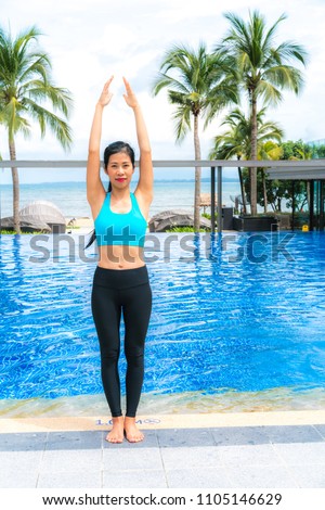 Portrait of young woman (fitness, yoga, perfect tanned body, healthy skin) at luxury swimming pool. Travel and Vacation. Freedom Concept. Outdoor shot