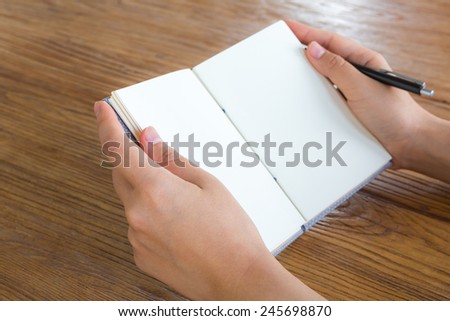 Hands with pencil and book on wood table
