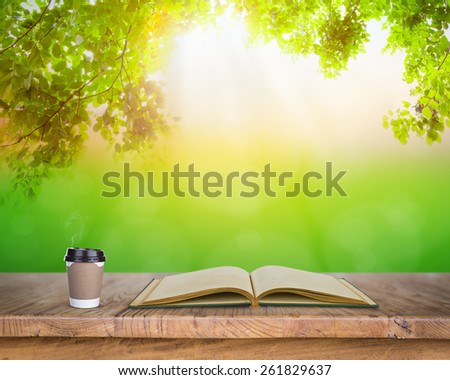 Paper cup of coffee and book on Wood table in nature