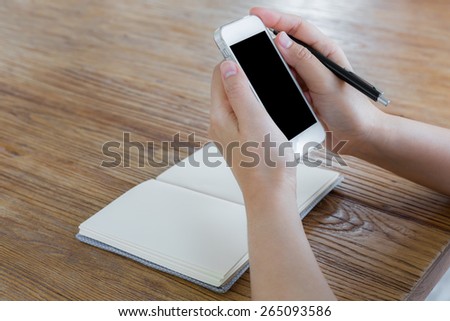 Woman using smart phone on the table with book