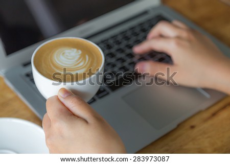 Closeup of business woman hand typing on laptop keyboard and coffee