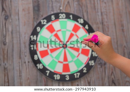 Hand holdin red arrow and throwing to dart board