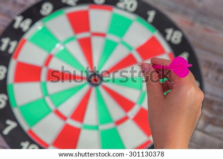 Hand holdin red arrow and throwing to dart board