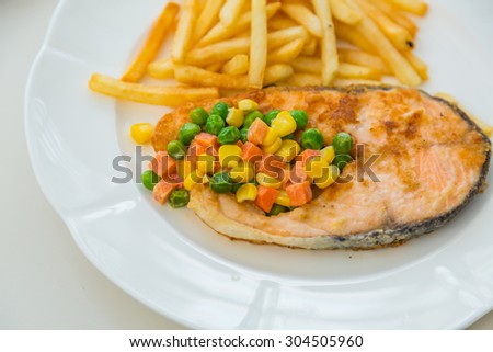 Grilled salmon steak meal served with salad and French fries
