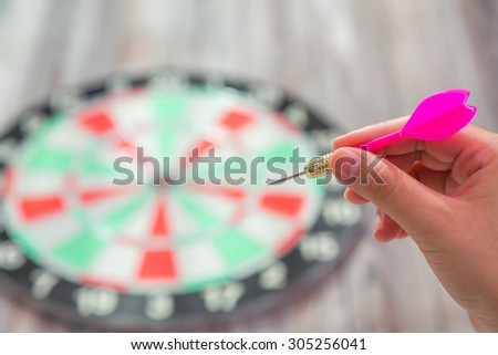 Hand holding red arrow and throwing to dart board