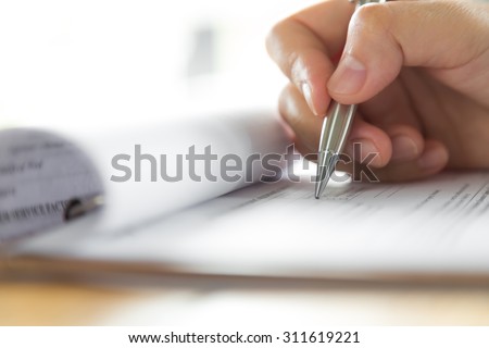 Hand with pen over application form
