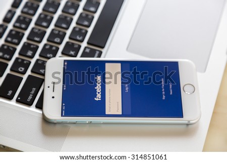 Loei, Thailand - August 12, 2015:  Iphone on laptop with mobile application for Facebook on the screen