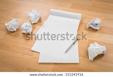 White note book paper with pencil and crumpled paper on a wooden desk