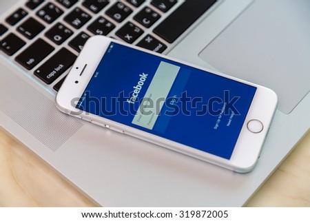 Loei, Thailand - August 12, 2015:  Iphone on laptop with mobile application for Facebook on the screen
