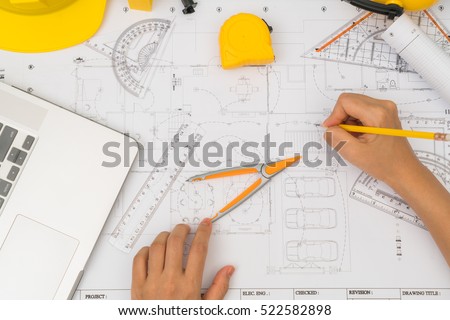 Hand over Construction plans with yellow helmet and drawing tools on blueprints