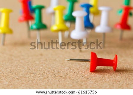 Group of colorful push pins on cork bulletin board.