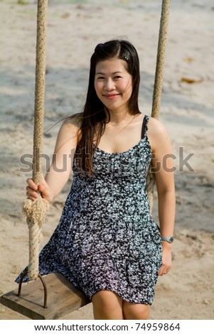 Girl sitting on rope swings on the beach