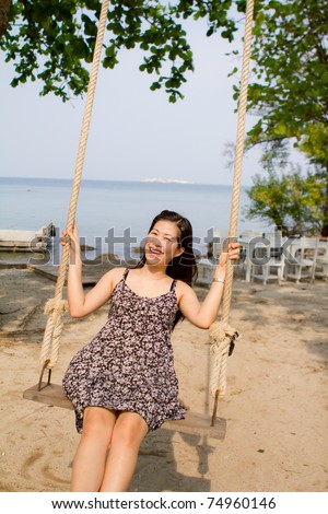 Carefree girl sitting on rope swings on the beach