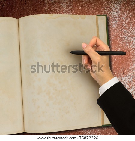 Hand writing in open old notebook on table
