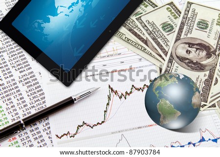 Business graph,touchpad, pen,earth and dollars on table