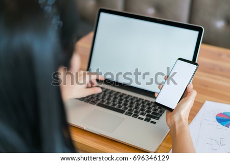 Business woman hand with Financial charts and mobile phone over laptop on the table