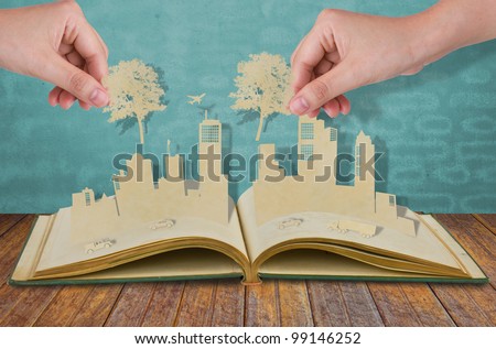 Hand hold paper cut  of tree over Paper cut of cities with car and plane on old book