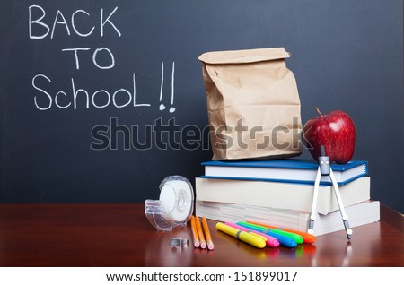 Back to school, school books with apple and  paper bag lunch on desk