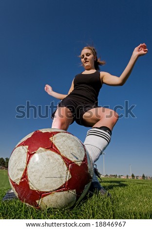 A female soccer player kicking the ball, main focus on the ball.