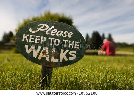 Sign in the grass with a man in the background breaking the rules