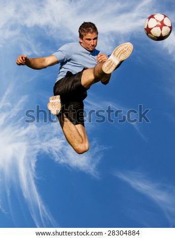 stock photo : Athletic male high in the air kicking a soccer ball