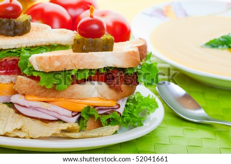 Close up of a Cub sandwich on a green place mat with yellow soup