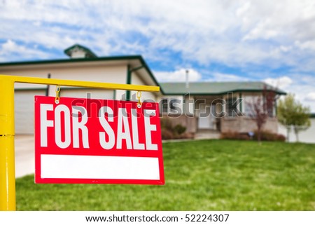 Real estate sign in front of a house for sale focus on the sign