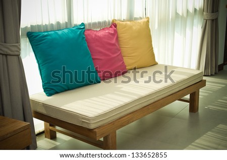 A long chair decorated with three color pillows