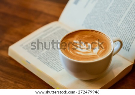 A cup of caffe latte place on a book or a novel
