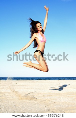 Fashion model in swimsuit jumping on the beach